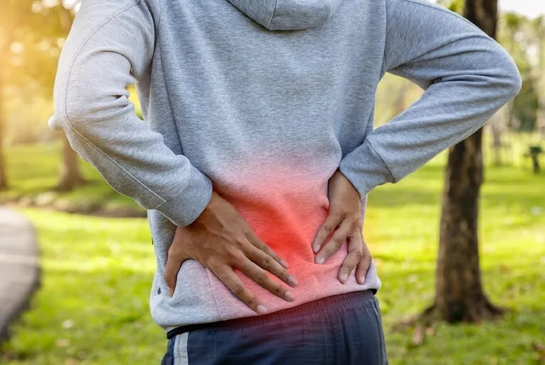 A person holding their lower back in discomfort